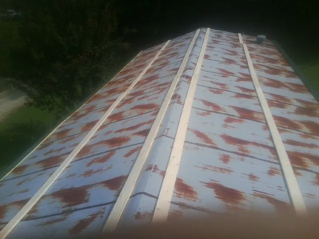Rusted metal roof panels with new wood purlins before replacement — Storm Damage Roof Repair in Blue Grass by Roofing Brothers