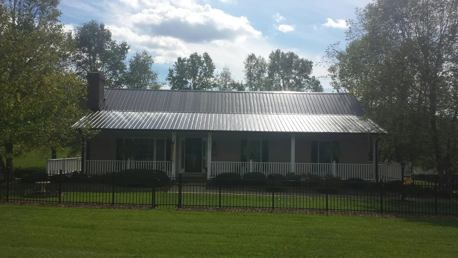 Gray metal roof on a brick ranch with a full width front porch — Gutter Guard Installation work by our crew in Blue Grass