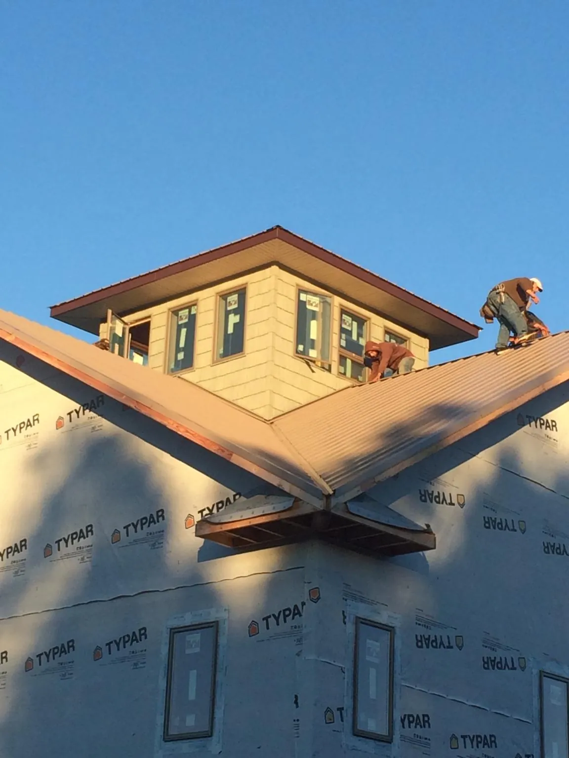 Roofers working around a rooftop cupola on a new metal roof at sunset — Roof Waterproofing in Blue Grass by Roofing Brothers